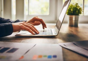Entrepreneur typing on a laptop opening a business account.