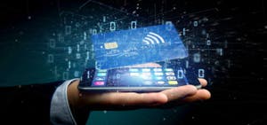 A hand holding a smartphone with a digital credit card hovering above, surrounded by data and binary code, symbolizing secure digital payments.